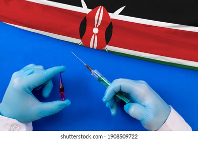 Kenya Vaccination. Hands Of Doctor Holding Syringe And Coronavirus (COVID-19) Vial Vaccine On Flag Kenya