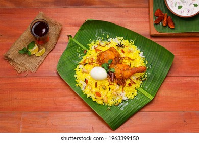 Kerala Chicken Dum Biryani ,arranged Traditionally In A Banana Leaf  And Raita As Side Dish And Hot Lemon Tea  With Wooden Background Or Texture,selective Focus