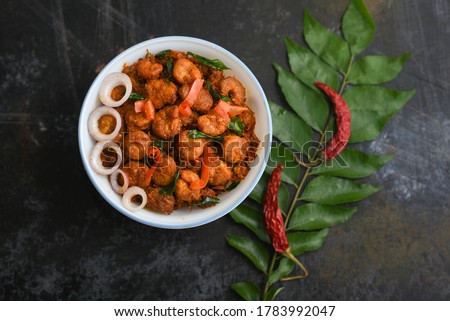Kerala fish curry Prawns, Chemmeen roast shrimp fry spicy prawns Masala in banana leaf plate on dark black background in South India. Top view popular Indian non veg food side dish for rice, Chapati