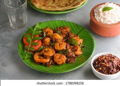 Kerala fish curry Prawns,Konju roast and Porotta or Chemmeen Ulathiyathu, shrimp fry Kerala fish curry spicy prawns in banana leaf plate on white background in South India. Popular Indian non veg food