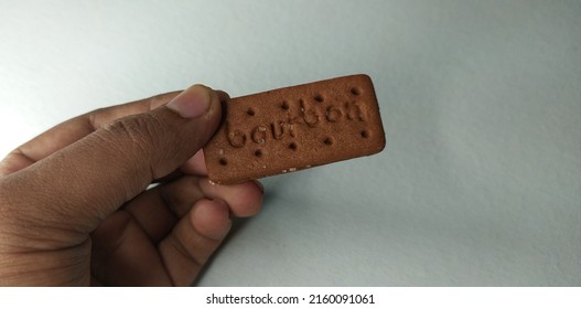 Kerala, India 24-May-2022 Hand Holding Typical Bourbon Chocolate Cream Filled Biscuit Or Cookie. Isolated On Plain White Table Background With Copy Space. Selective Focus Clouse Up Macro Top Side View