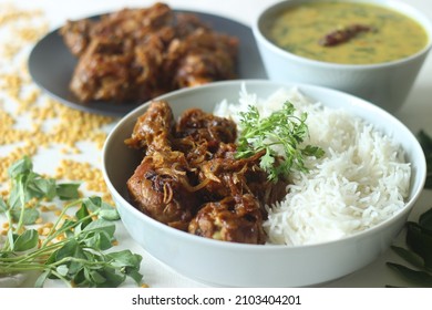 Kerala style dry chicken roast and lentil curry prepared with fenugreek leaves served with basmati rice. A healthy combination meal called rice with chicken and methi dal. Shot on white background