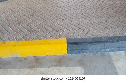 Kerb Stone Painted With Yellow And Block And Connecting Both Interlock Tiles And Tarmac Road