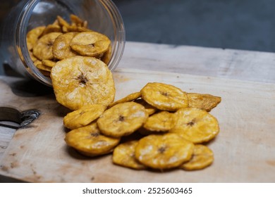 Keripik pisang or banana crackers a white glass jar at wooden cutting board. With copy space. Indonesian traditional snack made from banana and sugar. - Powered by Shutterstock