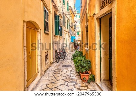 Kerkyra city narrow street view with yellow colorful houses and bikes during sunny day. Corfu Island, Ionian Sea, Greece