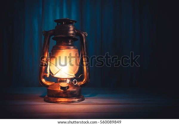 Kerosene lamp or lantern on a wooden background\
with dramatic lighting