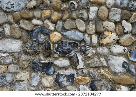 Kersey, UK - September 17 2023: Unknapped and few knapped nodules of flint, also flintstone, form of the mineral quartz used as building material in the construction of St Mary's Church Kersey.