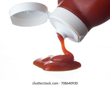Ketchup or tomato sauce falling from bottle on white background