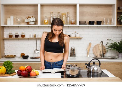 Keto, Detox Diet Food, Slimming And Weight Loss. Fit Slim Woman In Sporting Top Reading Recipe Book Before Cooking