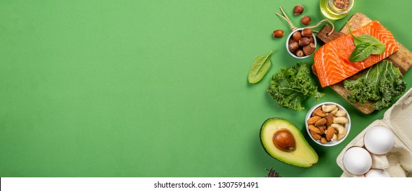Keto diet concept - salmon, avocado, eggs, nuts and seeds, bright green background, top view
