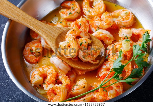 Keto diet dish shrimp scampi with\
garlic and butter sauce sprinkled with parsley, on a skillet on\
concrete background, horizontal orientation,\
close-up