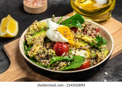 Keto diet plate quinoa, avocado, egg, tomatoes, spinach and sunflower seeds on dark background. Healthy food, ketogenic diet, diet lunch concept, Food recipe background. Close up.