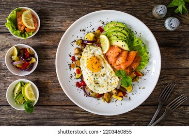 Keto Diet - Smoked Salmon, Sunny Side Up Egg, Avocado And Mix Of Vegetables On Wooden Table 