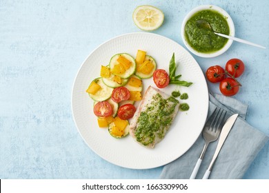 Keto dinner with white fish. Oven baked fillet of cod, pike perch with vegetables and pesto sauce. Healthy diet food, ketogenic paleo diet, Mediterranean cuisine. Blue background. Top view, copy space