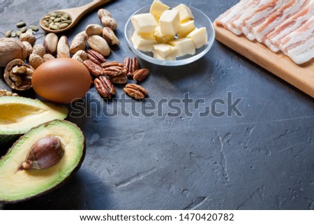 Keto food: avocado, eggs, butter, bacon, nuts on dark background. 