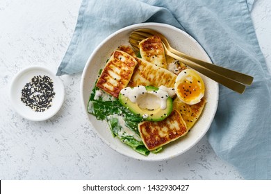 keto ketogenic diet soft boiled eggs with grilled haloumi, avocado and lettuce, mediterranean cuisine on pastel background