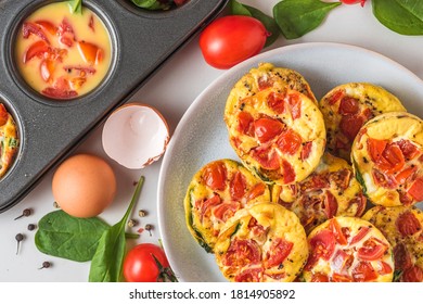 Keto Or Low Carb Diet Breakfast. Egg Cups Or Omelet With Spinach And Tomatoes In A Plate And Muffin Cups On White Background. Cooking Concept. Top View