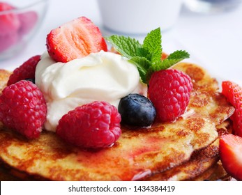 Keto pancakes made of coconut flour or almond flour, served with berries and whipped cream