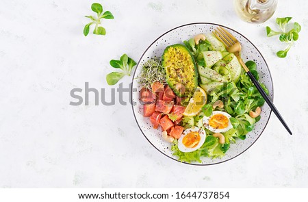 Ketogenic diet breakfast. Salt salmon salad with greens, cucumbers, eggs and avocado. Keto/paleo lunch. Top view, overhead