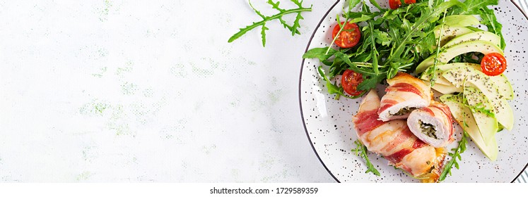 Ketogenic diet. Dinner dish with chicken meat roll wish  bacon, avocado, tomatoes and arugula. Detox and healthy concept. Keto food. Overhead, top view, banner