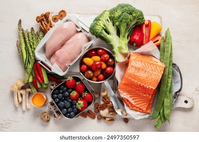 Ketogenic diet food. Healthy low carbs products. Keto diet concept. Vegetables, fish, meat, nuts, seeds, berries, cheese on a white background, top view.