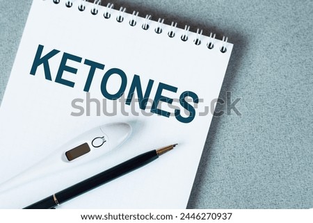 KETONES text written on notepad with a black pencil and electronic thermometre on it on blue surface Medical concept
