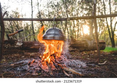 kettle is heated on a bonfire.  travel in the forest. Outdoor recreation concept. Teapot over the fire. Beautiful campfire in a tourist camp in the autumn forest with a hatchet on background - Powered by Shutterstock