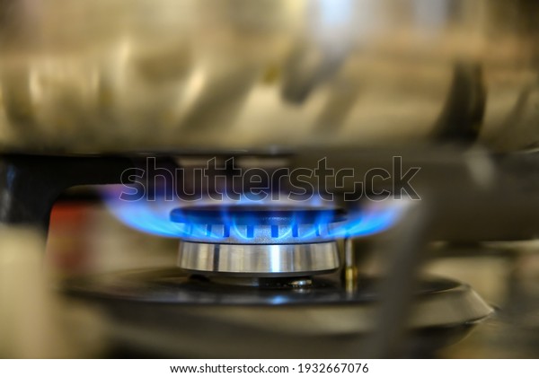 Kettle heats water on a gas stove, burning\
domestic gas close-up.
