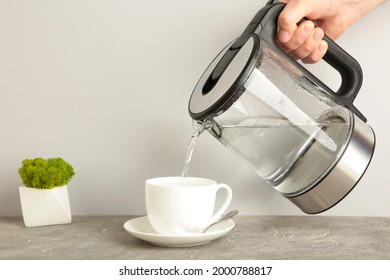 Kettle Pouring Boiling Water Into A Cup On Grey Background. Top View.