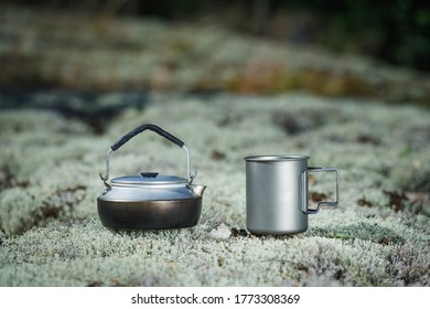 Kettle And Titanium Mug On Moss. Background Is Blurry.