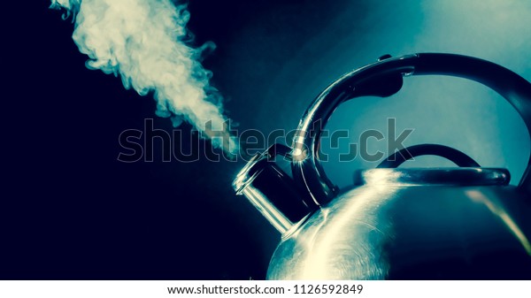 Kettle whistling,\
boiling kettle with steam texture on a black background. Vintage,\
grunge old retro style\
photo.