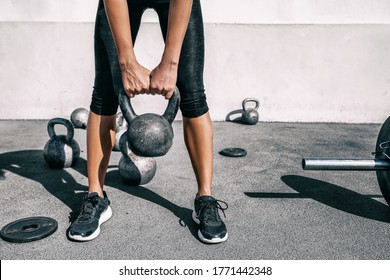Kettlebell weightlifting athlete woman lifting weight at outdoor fitness gym. Lower body legs and feet closeup of strength training legs, glutes and back lifting free weights.