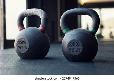 Kettlebells on the ground in a gym, focus is on the red kettlebell
