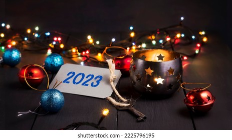 Key with 2023 tag. Glowing New Year's garland and decorations on a wooden table. New Year card. Festive foyer. Background.