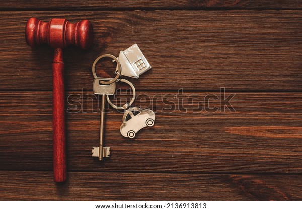 The key to the apartment with\
a keychain and car in the shape of a house on wooden\
background.