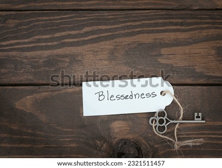 The key of blessedness concept isolate. Silver key with a label on wood table.