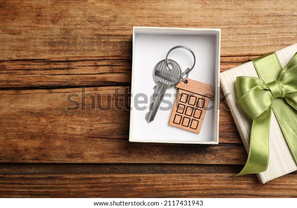Key with bow in gift box on wooden\
table, flat lay and space for text. Housewarming\
party