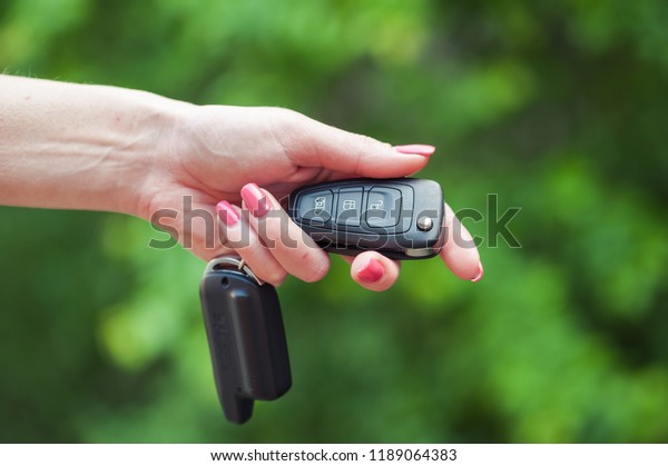 Key from the car in a female hand. Car seller.\
Opening and signaling