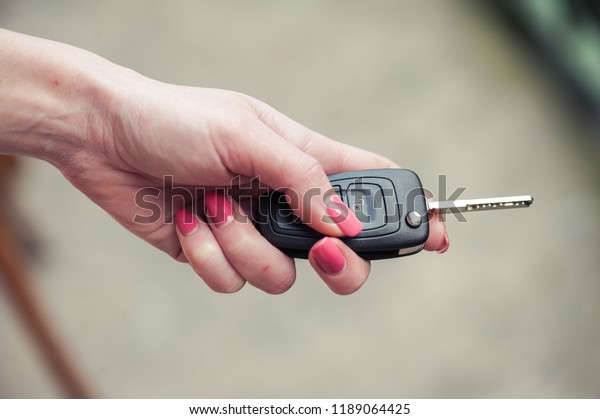 Key from the car in a female hand. Car seller.\
Opening and signaling