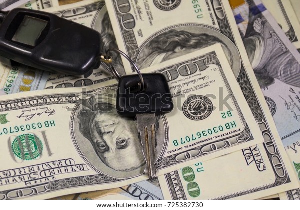 Key with car\
key ring on background of American one hundred dollar bills.\
Concept of buying and selling a\
car