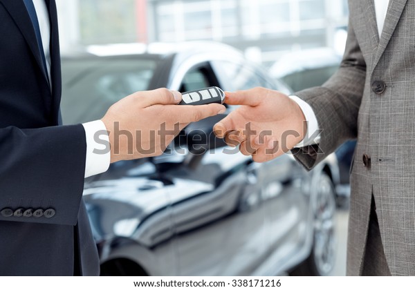 The key. Close up shot of a car dealer passing\
car keys to the customer