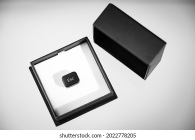 The key of a computer keyboard with the inscription Esc inside an elegant package of jewelry, the composition expresses the concept of escape from a couple relationship, monochrome image.