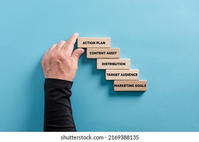 Key concepts or steps for developing an effective marketing content strategy. Male hand arranges a wooden block ladder. - Shutterstock ID 2169388135