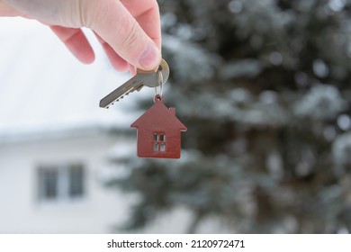 Key in hand on the background of the house. House in the forest, near the trees. - Shutterstock ID 2120972471