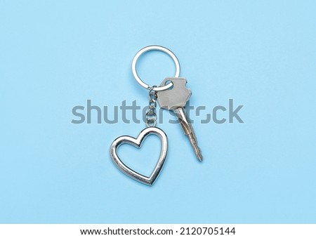 Key with heart shaped keychain on blue background