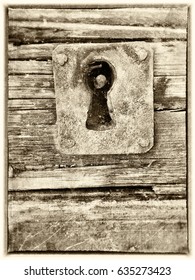 Key Hole In Old Wooden Door Textured With Scratches And Stains In Sepia Tones With Frame And Copy Space.  