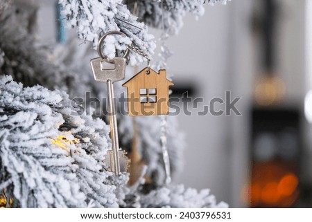 Key to the house with a keychain is hanging on the Christmas tree. A gift for New Year, Christmas. Building, design, project, moving to new house, mor