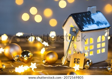 Key to the house with a keychain on a lamp with a Christmas decor. A gift for New Year, Christmas. Building, design, project, moving to new house, mortgage, rent and purchase real estate. Copy space