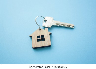 Key and house shaped keychain arrangement on blue background. Top view, flat lay. Real estate, insurance concept, mortgage, buy sell house, realtor concept
