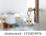 Key with keychain in a house shape in the door keyhole. Buy new home concept. Real estate market.